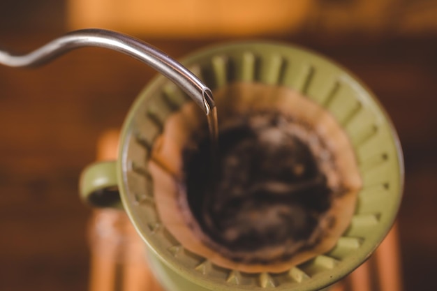 Barista hipster versant de l'eau chaude pour faire du café avec un style goutte à goutte ou filtre dans un café infusion lente pour une boisson aromatisée à la caféine dans une tasse de café noir frais et d'espresso pour le petit déjeuner