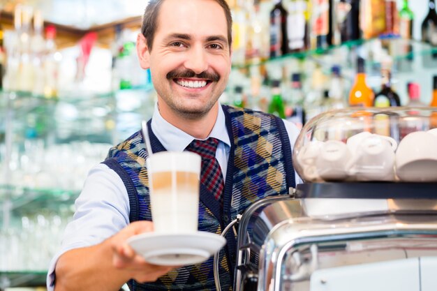 Barista in coffee bar propose un café au lait en verre