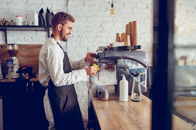Barista masculin souriant à l'aide d'une machine à café dans un café