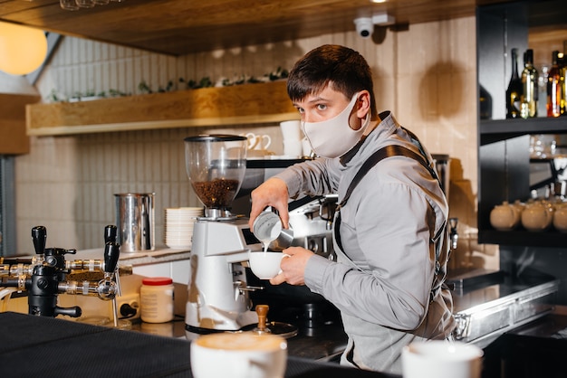 Un barista masqué prépare un délicieux café au bar dans un café