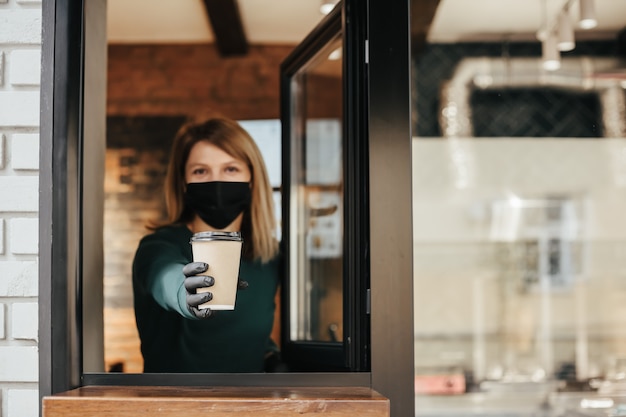 Photo un barista masqué renverse du café par la fenêtre à cause d'un coronavirus
