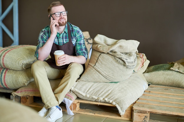 Barista moderne assis sur des sacs avec du café