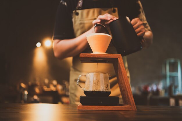 Barista préparant un filtre à café le matin, boisson à l'arôme d'espresso noir frais, boisson chaude dans une tasse de café, caféine brune sur fond de magasin de bar