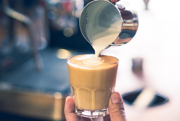 Barista préparant un latte glacé d'humeur artistique dessinant un motif au café