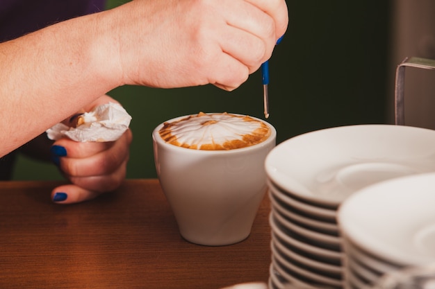 Barista préparant une tasse de café latte art avec un appareil en métal spécial - outil stylo latte-art