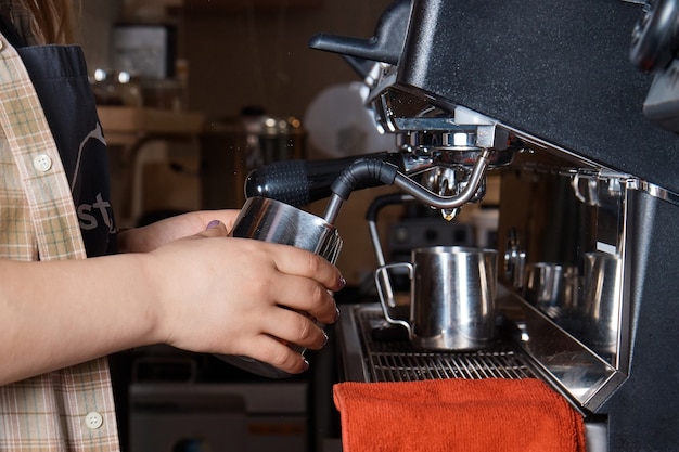 Barista prépare et verse du café dans une tasse sur la machine à café, gros plan, mains d'une femme, surface floue