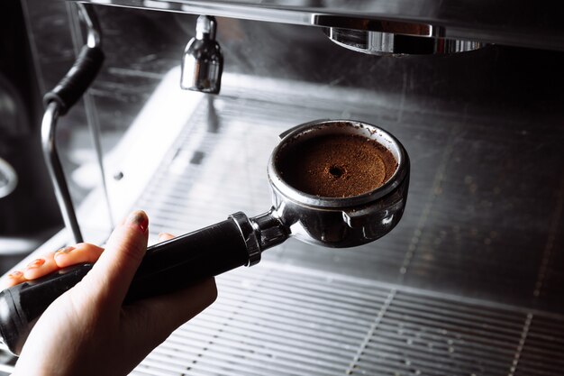 Barista pressant le café moulu dans un porte-filtre par une machine à café inviolable préparant du café frais