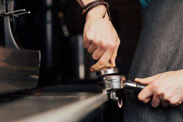 Barista presse le café moulu à l'aide d'un tamper