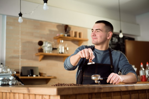 Le barista presse du café moulu à l'aide de tamper dans un café.