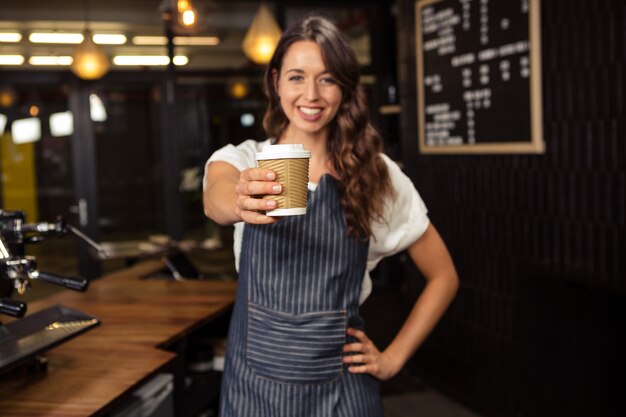 Barista souriant tenant une tasse jetable