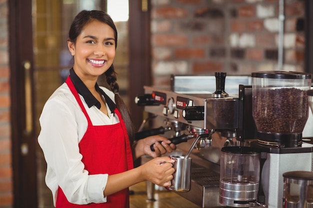 Barista souriant à la vapeur de lait à la machine à café