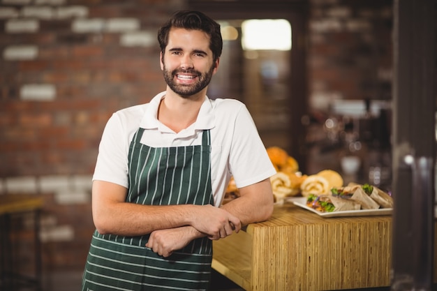 Barista souriante s'appuyant sur le comptoir