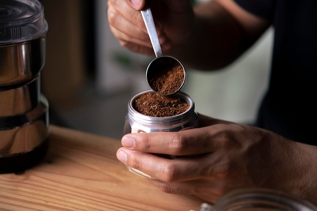 Barista tenant un pot de moka avec du café moulu dans un café
