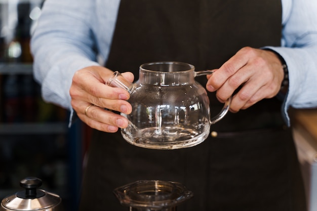 Barista tourne dans les mains et regarde le pot avec du café avant de faire aeropress