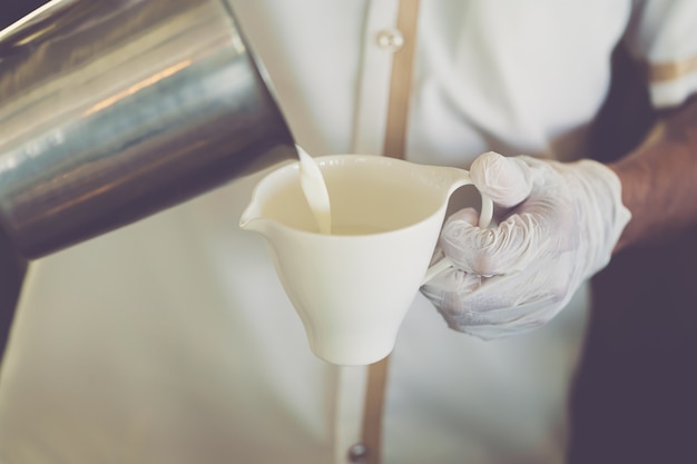 Barista travaillant avec des gants tout en versant du lait chaud Mesures de protection au travail pendant un Covid19