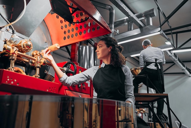 Barista vérifiant les grains de café dans la machine d'usine Vue de dessous