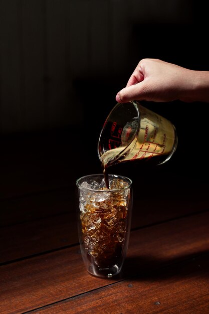 Barista versant du lait dans un verre de café glacé