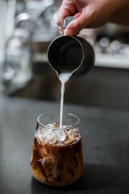 Barista versant du lait dans un verre