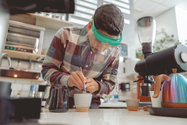 Barista en visière de protection faisant un motif sur le café