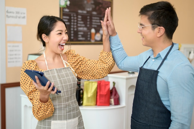 Baristas utilisant une tablette vérifiant les revenus de l'entreprise, marketing d'entreprise réussi dans un café