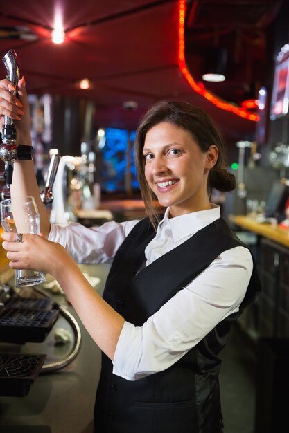 Barmaid heureux tirant une pinte de bière