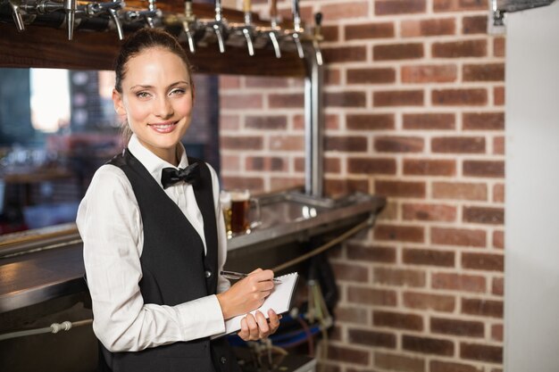 Barmaid prenant les commandes sur le bloc-notes