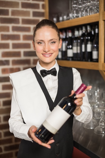 Barmaid tenant une bouteille de vin