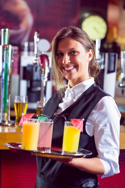 Barmaid tenant un plateau de cocktails