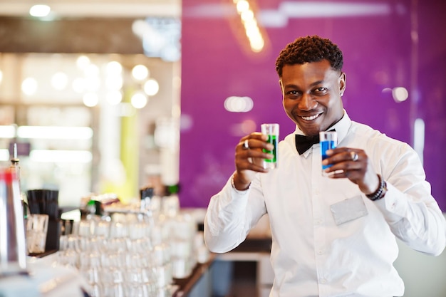 Barman afro-américain au bar tenant deux coups de cocktail Préparation de boissons alcoolisées