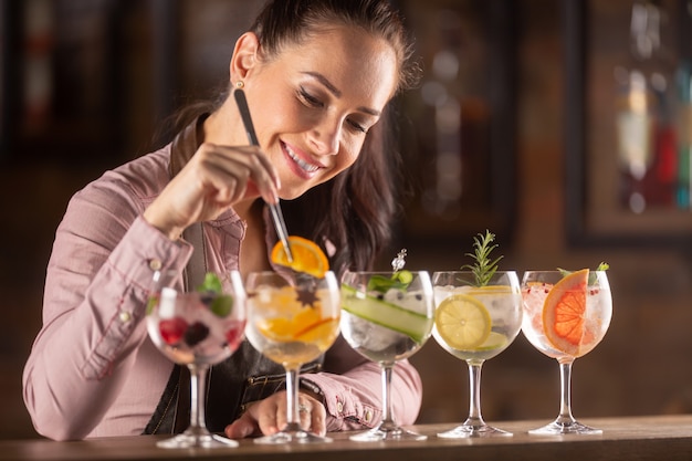 Barman aimant son travail décore des cocktails gin tonic dans des verres sur un bar.