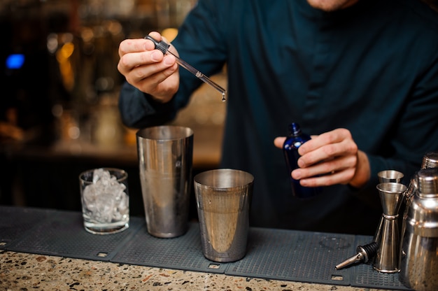 Barman ajoutant du colorant bleu dans un shaker faisant un cocktail d'été