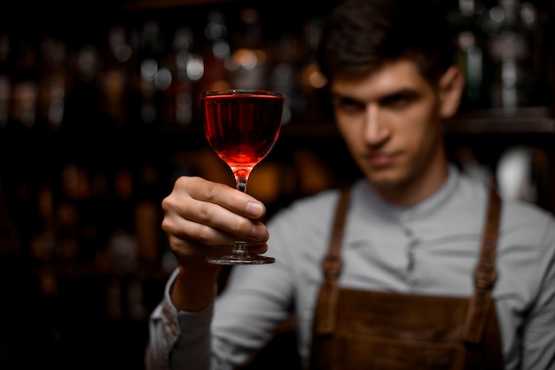 Barman attrayant servant un cocktail alcoolique rouge dans le verre