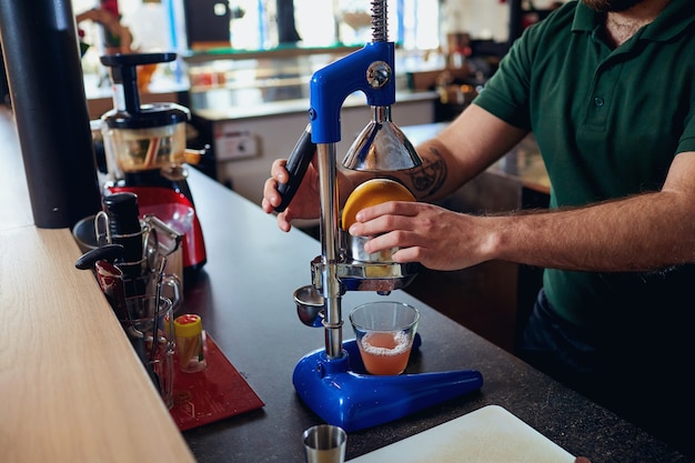 Le barman barista fait du jus fraîchement pressé sur la machine