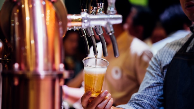 Photo barman ou barman versant une bière du robinet de bière