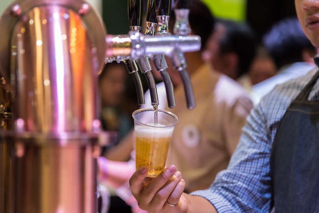 Barman ou barman versant une bière du robinet de bière