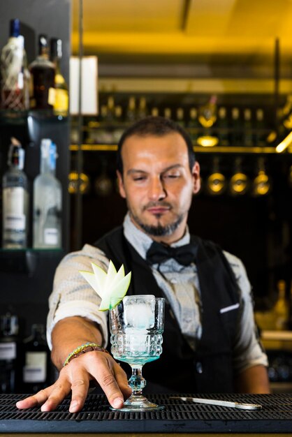 Photo barman avec une boisson sur le comptoir debout dans le bar