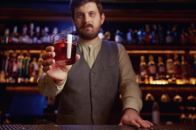 Barman donnant un cocktail fraîchement préparé en gros plan à la main avec du verre