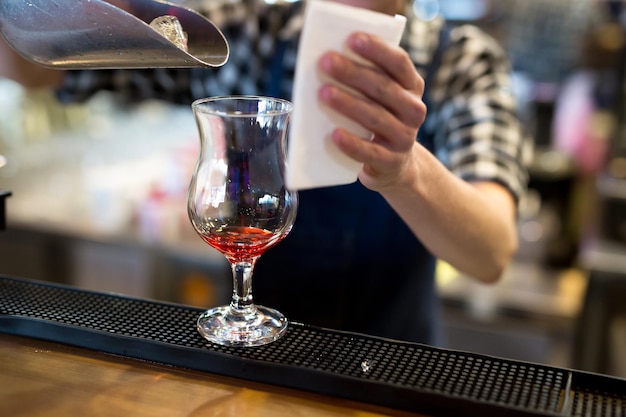 Le barman du restaurant verse de la glace dans un verre à cocktail.