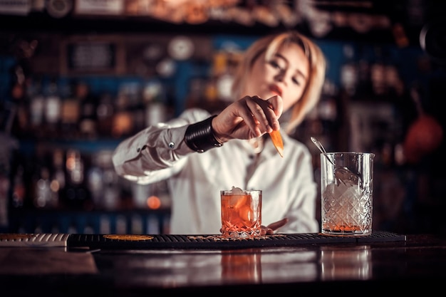 Une barman expérimentée montre le processus de préparation d'un cocktail tout en se tenant près du comptoir du bar dans une discothèque