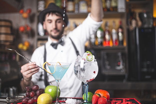 Barman expert faisant un cocktail en boîte de nuit avec chapeau et noeud papillon