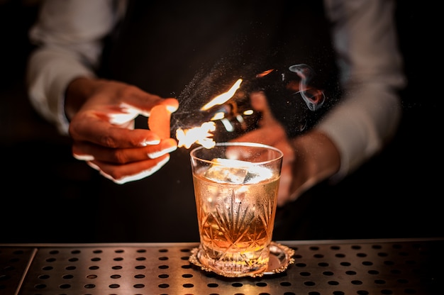 Barman faisant un cocktail d'été à l'ancienne frais et savoureux avec des notes d'écorce d'orange et de fumée