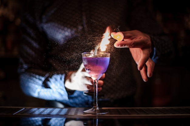 Barman faisant un puissant cocktail d'été violet avec une note de fumée