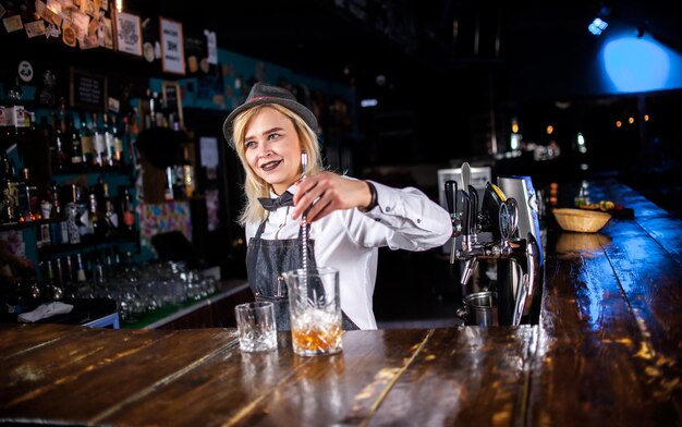 Le barman de fille formule un cocktail au pothouse