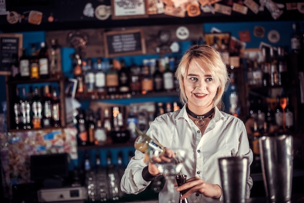 Le barman de fille formule un cocktail sur la salle