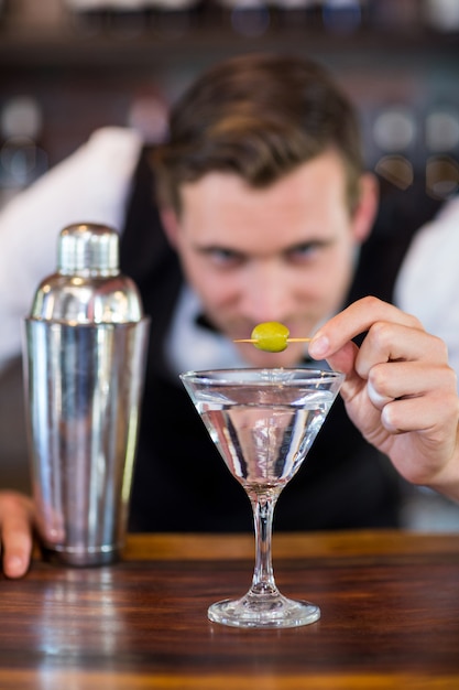 Barman garnissant un cocktail aux olives