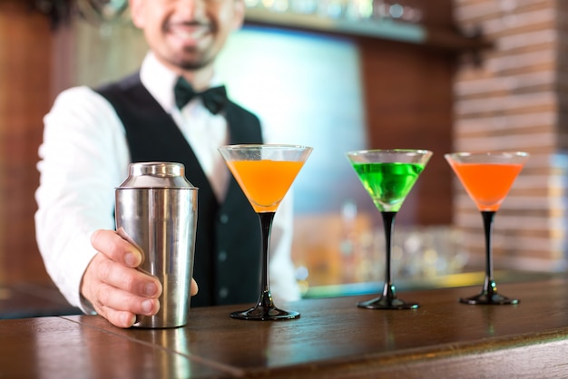 Le barman joyeux montre comment il prépare des cocktails.