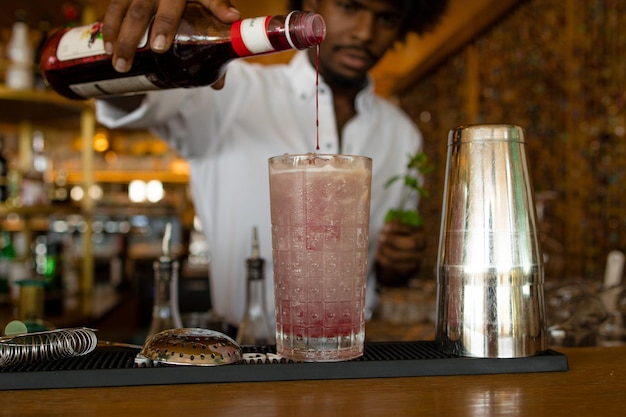 Un barman latin aux cheveux bouclés qui sert de la grenadine.