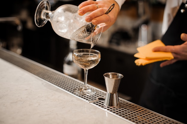 Barman main verser une boisson alcoolisée mélangée avec de la glace dans un verre