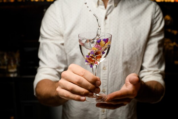 Barman masculin présentant un cocktail dans le verre décoré de fleurs