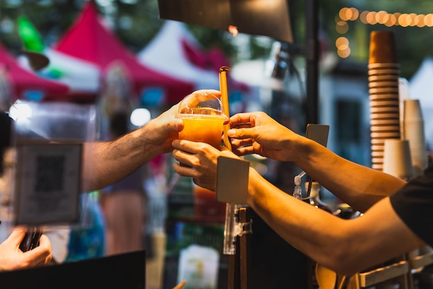 Barman masculin servant une boisson saine au client dans un verre à emporter en plastique